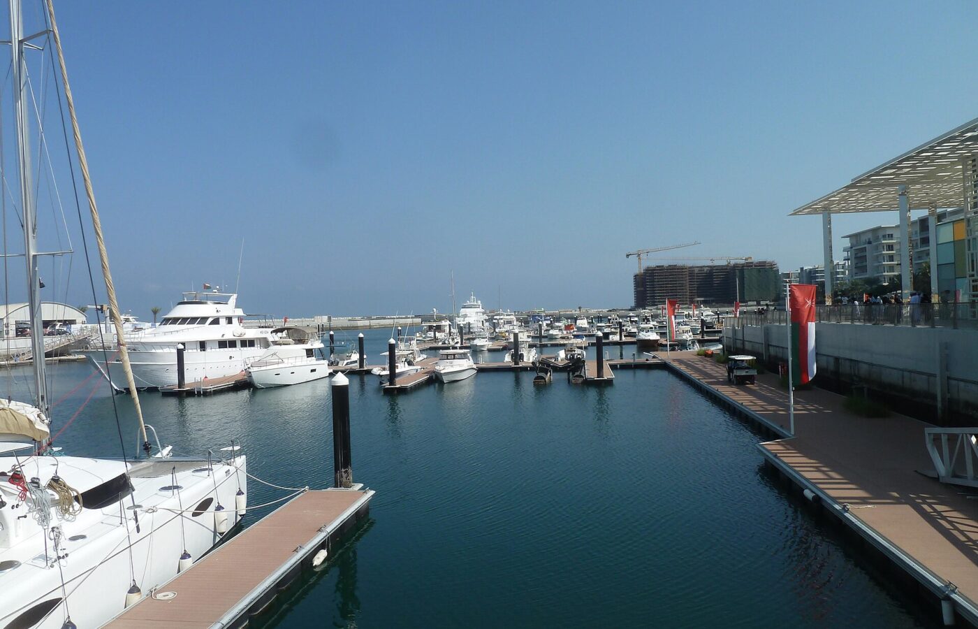 Yachts moored at Al Mouj Marina with waterfront buildings behind