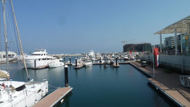 Yachts moored at Al Mouj Marina with waterfront buildings behind