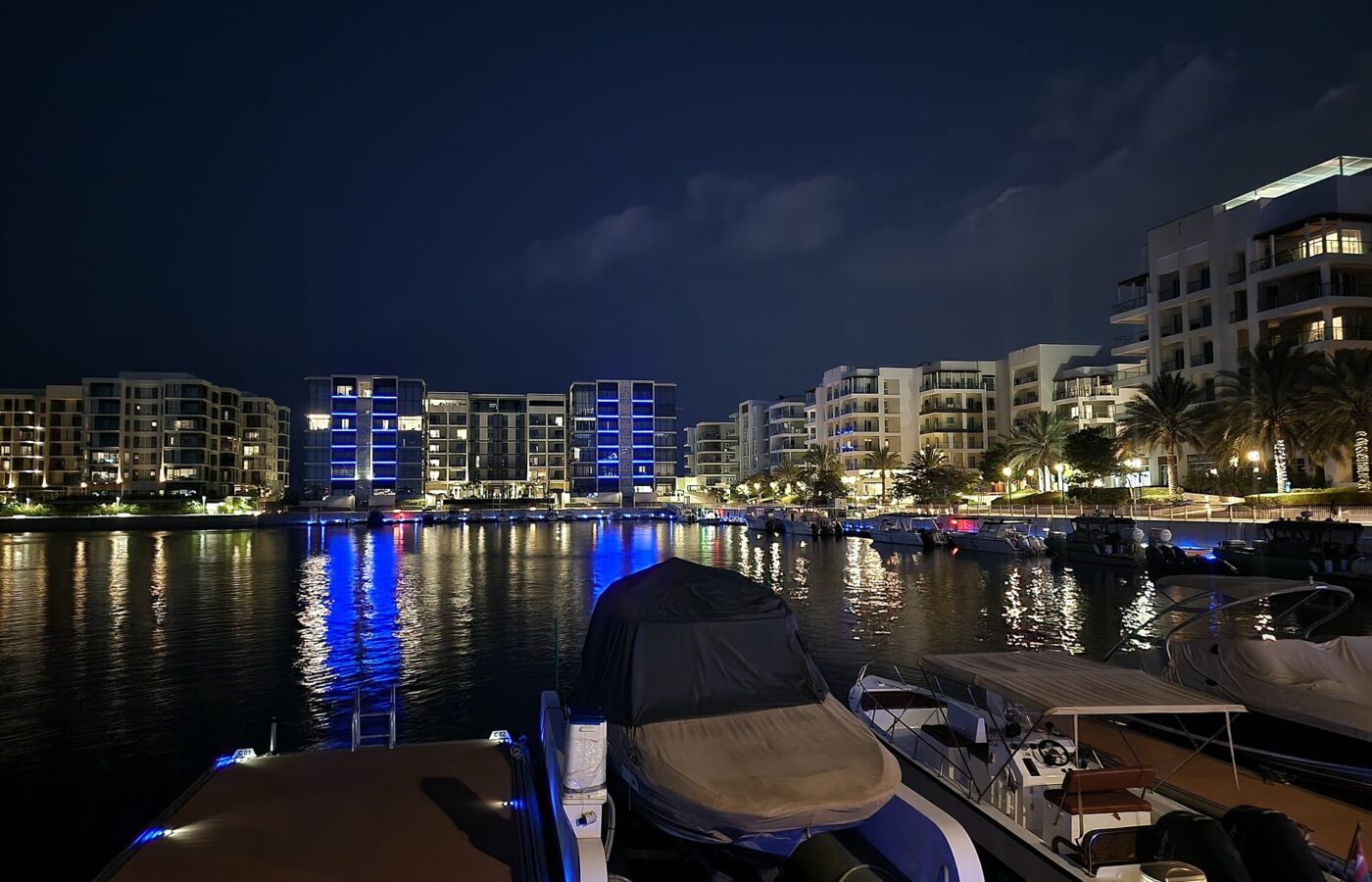 Apartment buildings lit up at night around Al Mouj Marina, Muscat