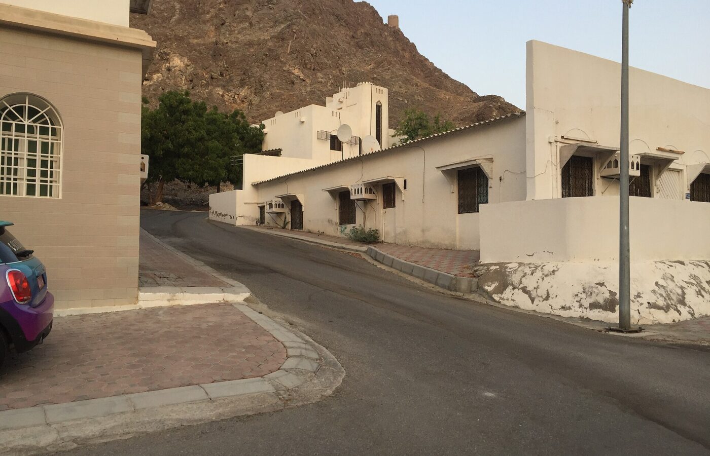 A residential street of Omani villas in Muscat with a rocky hillside behind