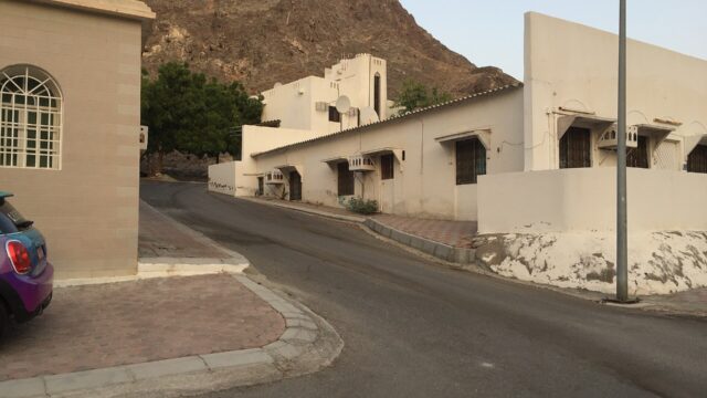 A residential street of Omani villas in Muscat with a rocky hillside behind