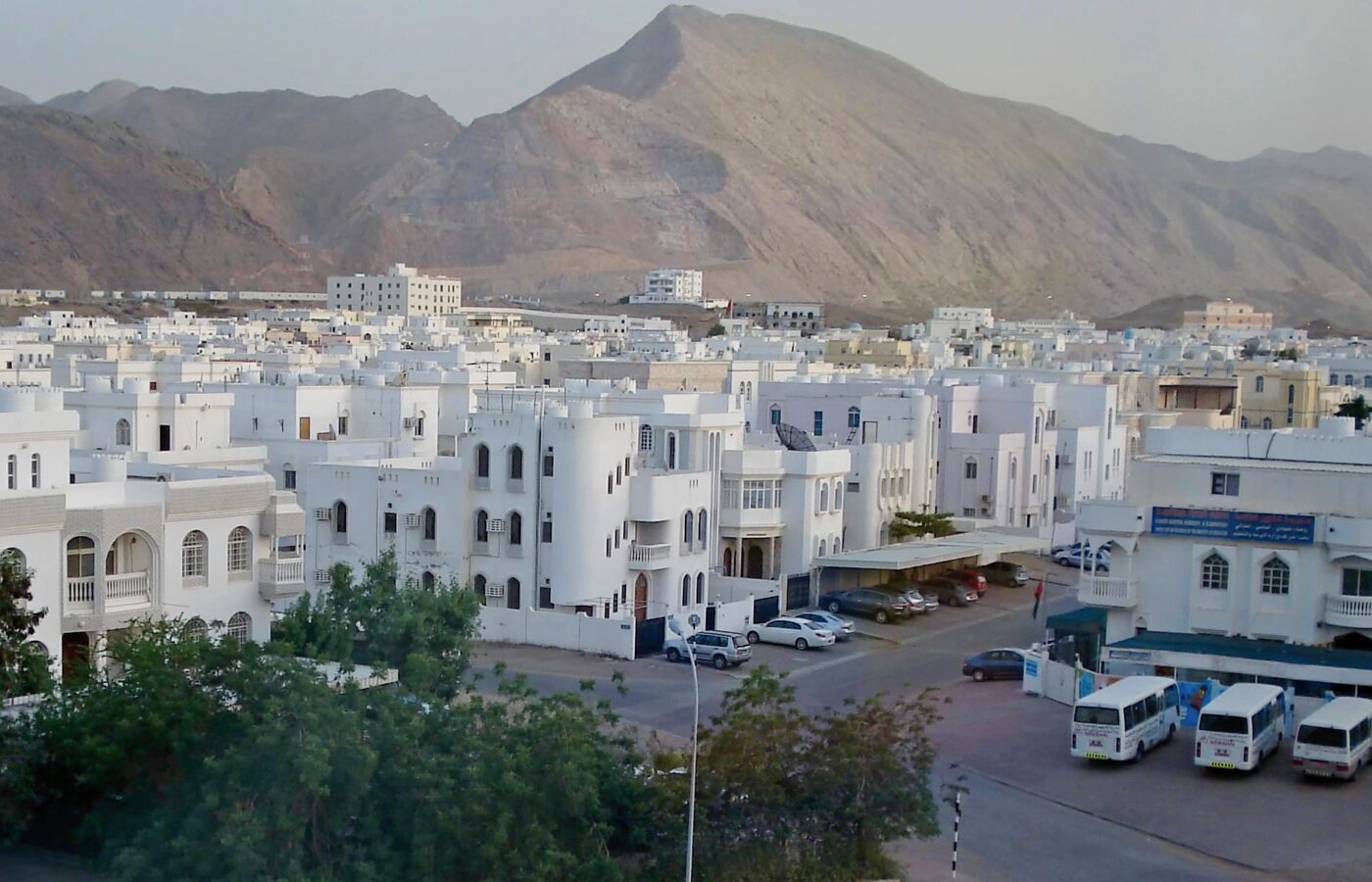 White low-rise residential buildings in Al Khuwair, Muscat, below the Al Hajar mountains