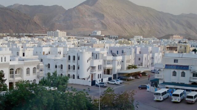 White low-rise residential buildings in Al Khuwair, Muscat, below the Al Hajar mountains